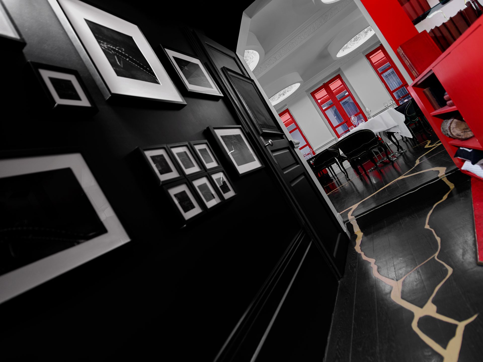 Boutary — vue 20 — couloir aux photographies encadrées noir et blanc, sol parquet noir et kintsugi or, ouverture sur salle