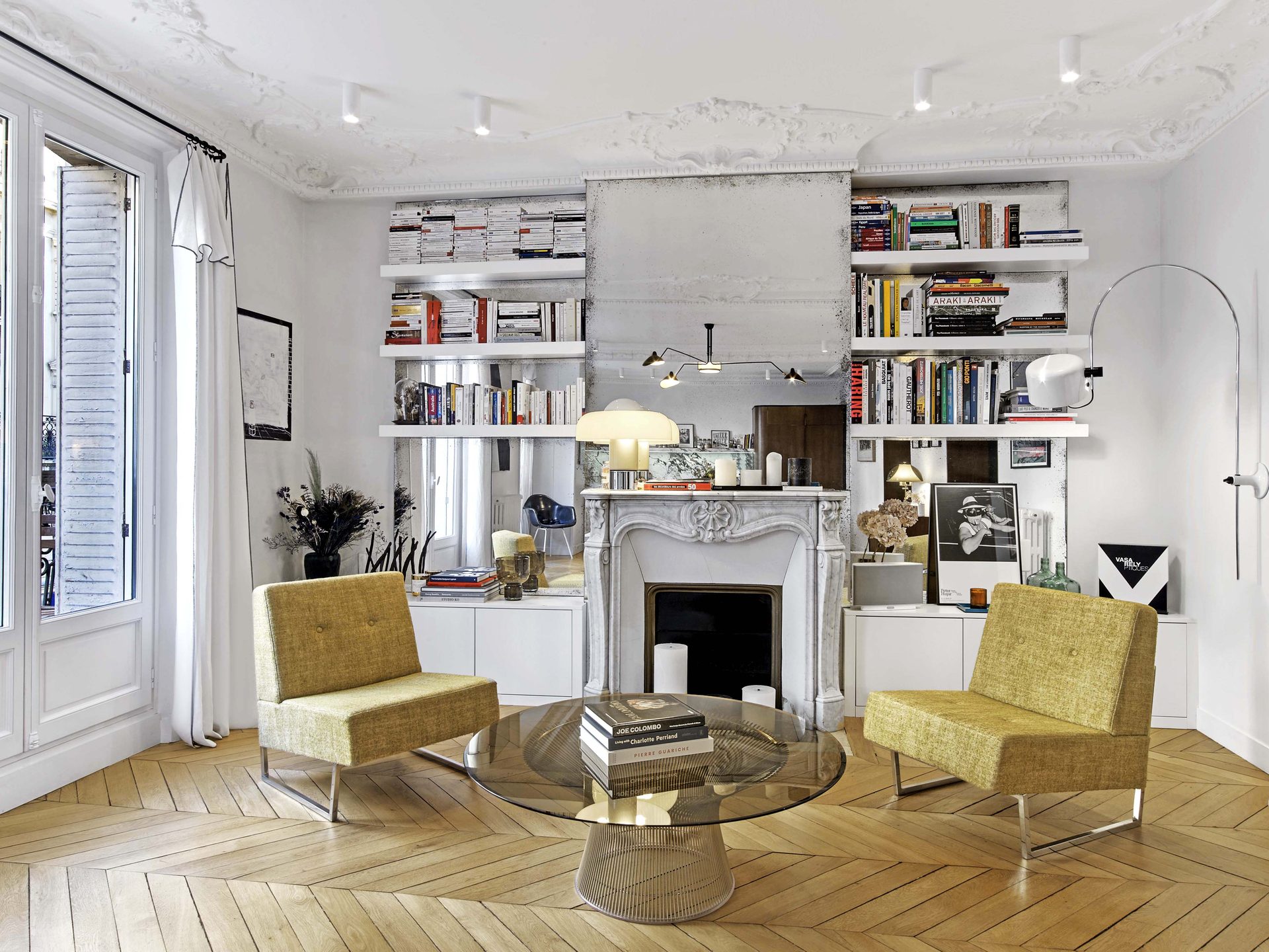 Salon symétrique : cheminée en marbre blanc, miroirs piqués et fauteuils moutarde vintage