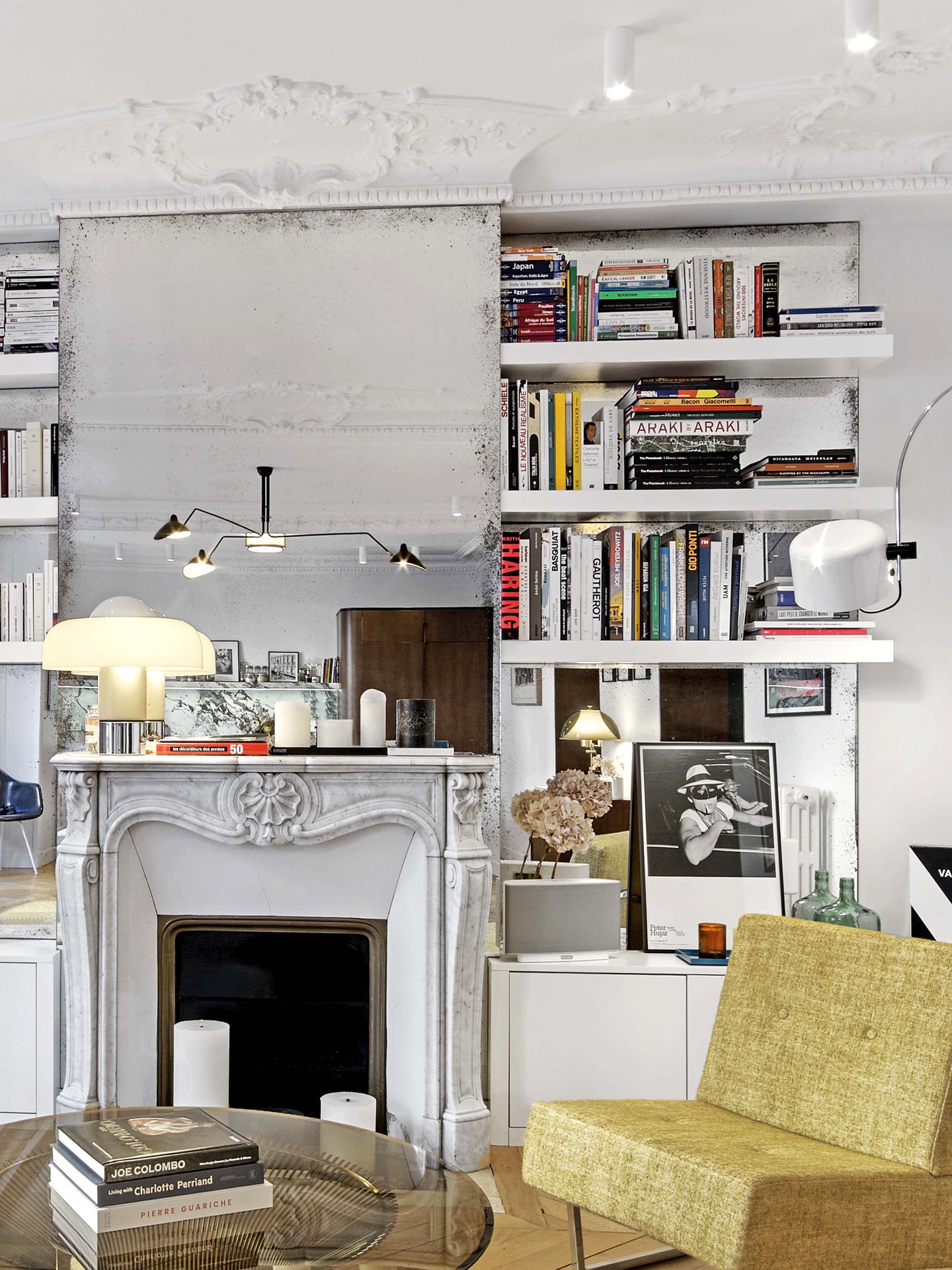 Salon vu sur la cheminée centrée et la bibliothèque sur miroir piqué