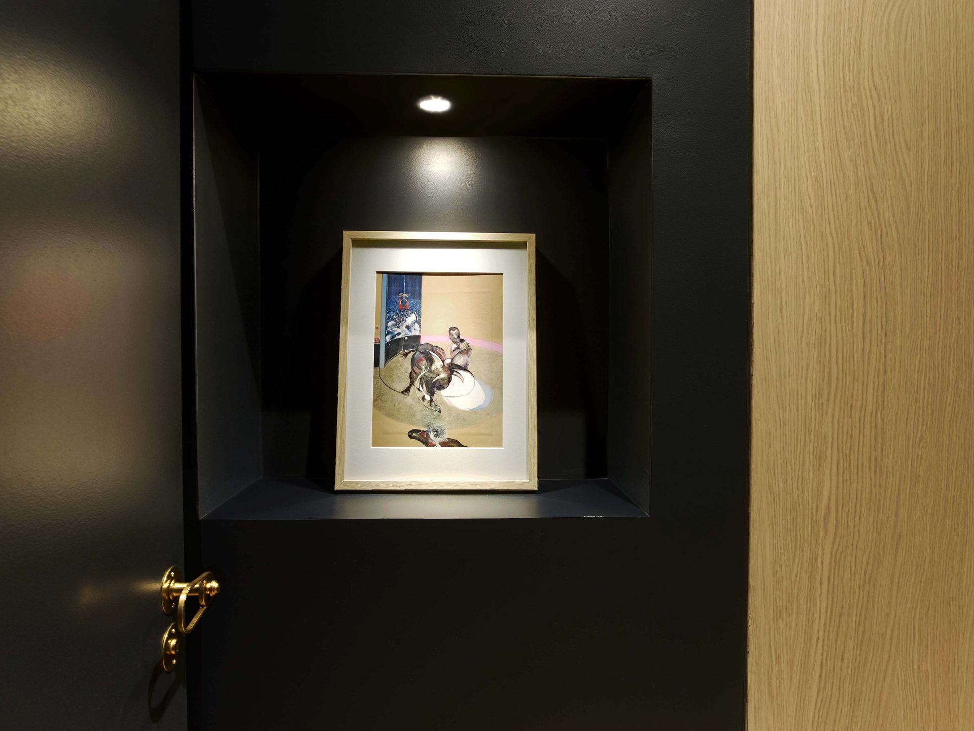 Niche éclairée présentant un cadre de Francis Bacon à côté d'une porte en chêne
