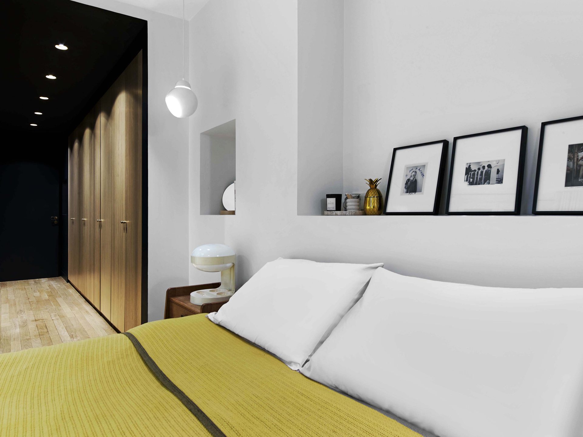 Chambre avec lit, jeté jaune, dressing en chêne et suspension Aalto
