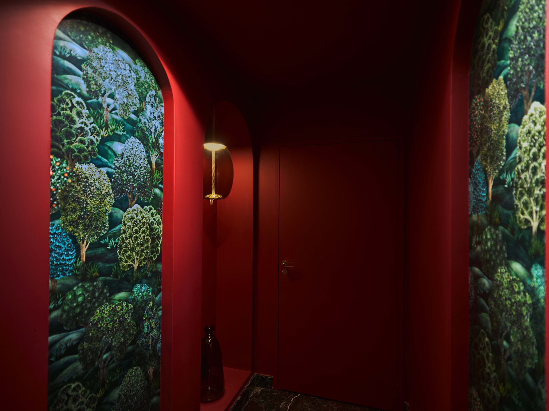 Couloir des toilettes : arches rouge bonbon et papier peint paysage forêt à la française
