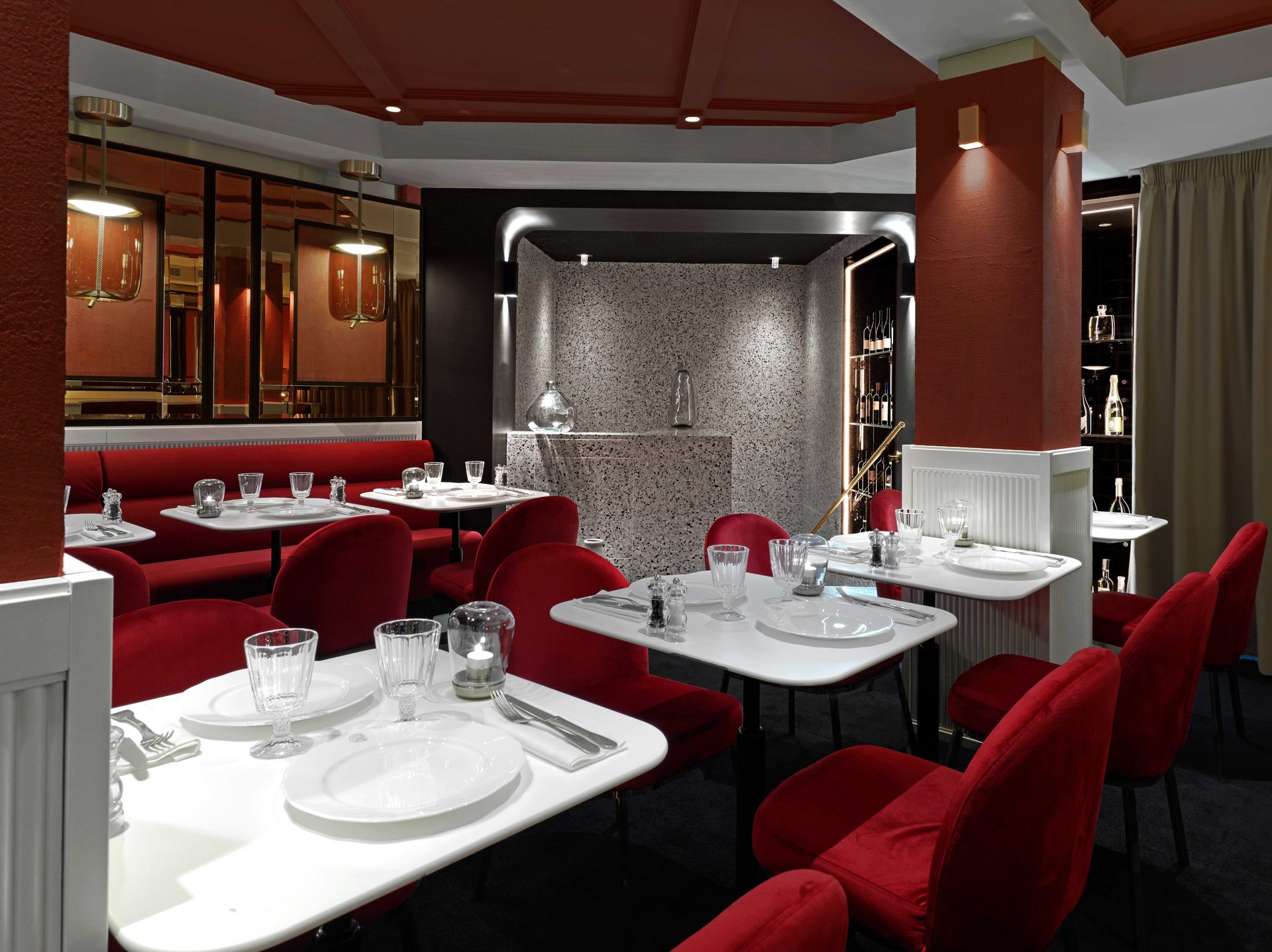 Salle rouge : niche terrazzo et cave à vins en arrière-plan, tables dressées au premier plan