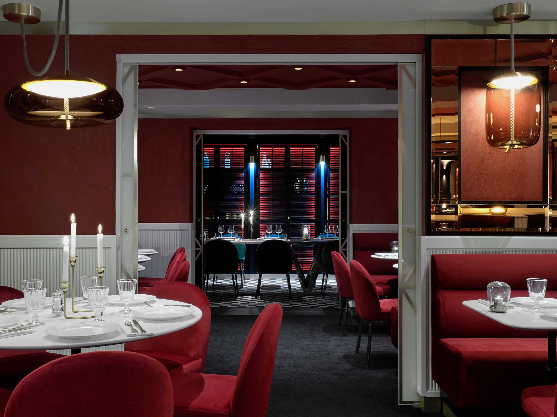 Salle haute rouge en plan large : tables dressées et ouverture sur le privatif noir aux stores rouges en arrière-plan