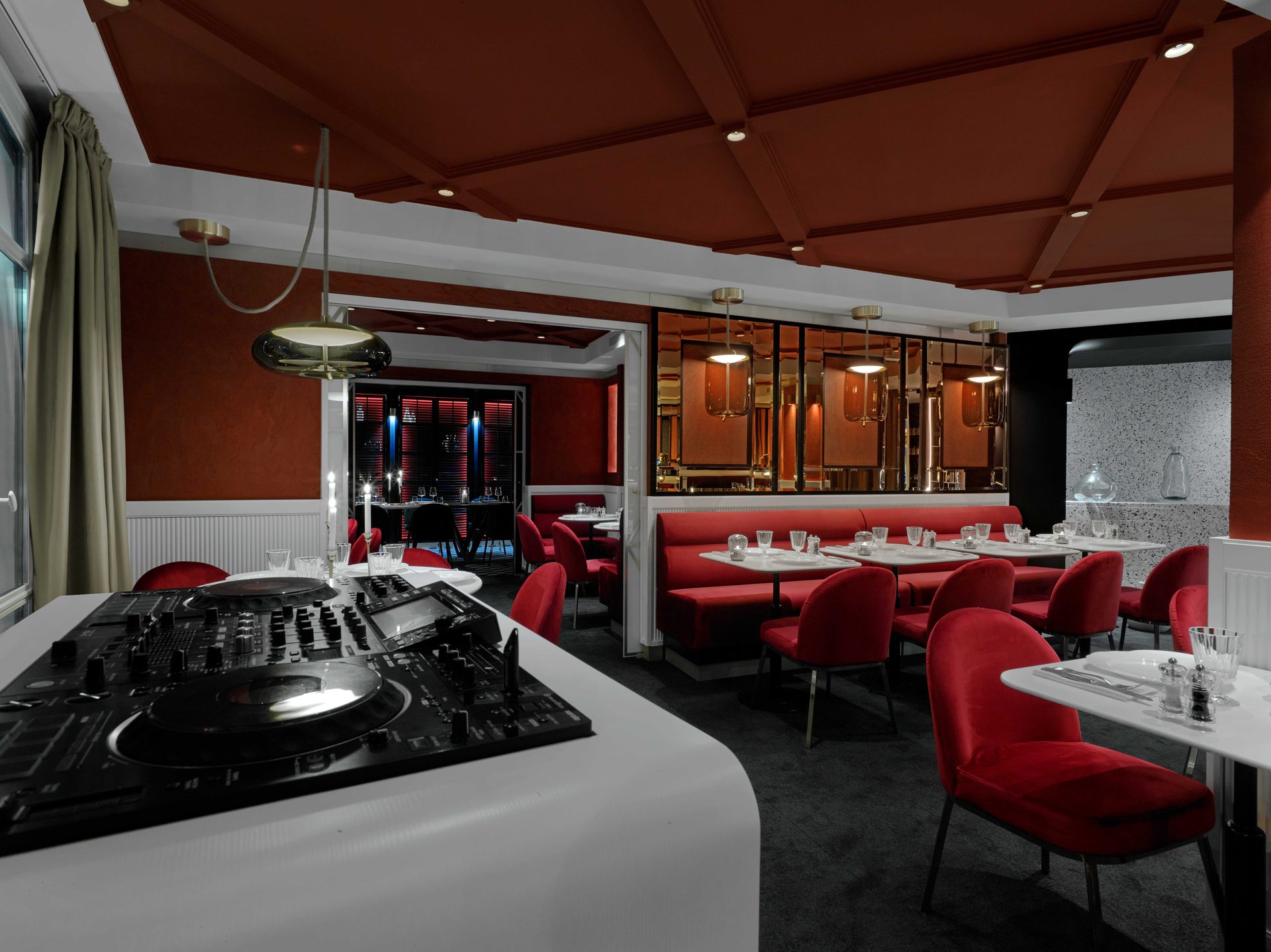 Guisé Trattoria — salle rouge haute avec console DJ au premier plan et ouverture sur le privatif noir
