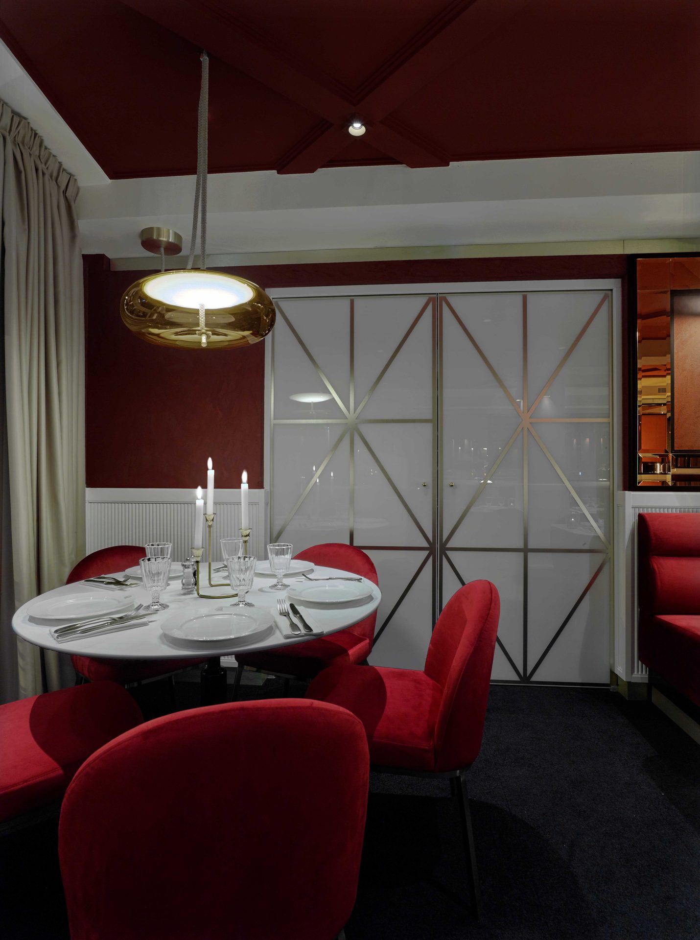 Guisé Trattoria — séquence portes salle rouge 1/3, table ronde dressée face aux portes coulissantes fermées à motif géométrique laiton