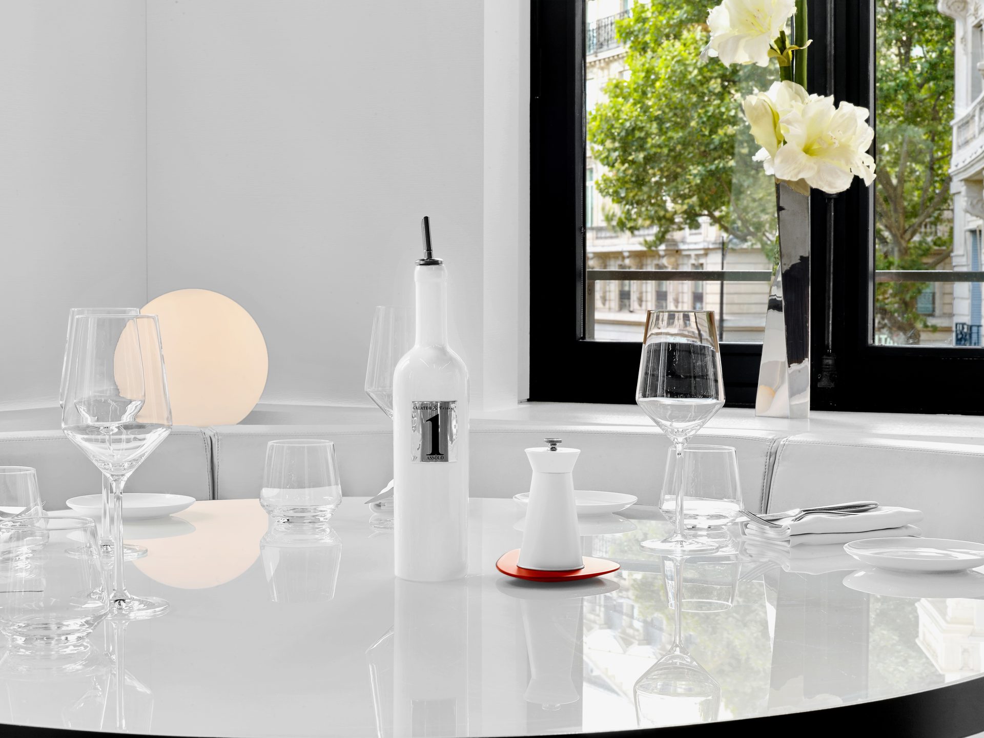 Nolita Paris — vue 08 — détail de dressage, verres en cristal et amaryllis dans vase inox, façade haussmannienne à travers la baie