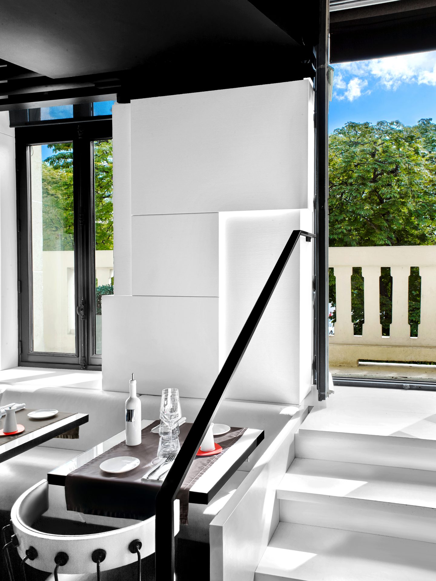 Nolita Paris — vue 13 — niveau mezzanine, table dressée près de l'escalier, parois blanches Wilmotte sculptées par la lumière