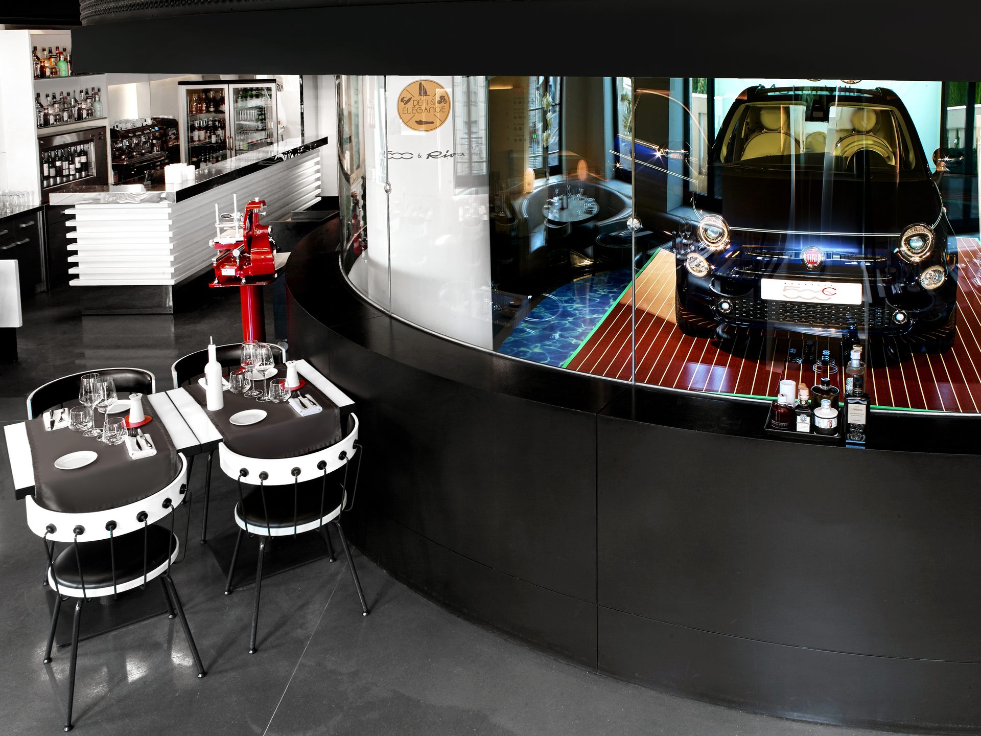 Nolita Paris — vue 15 — perspective de salle vers l'alcôve Fiat 500, mobilier circulaire en enfilade et vitrine ronde noire à droite, trancheuse Berkel rouge au bar