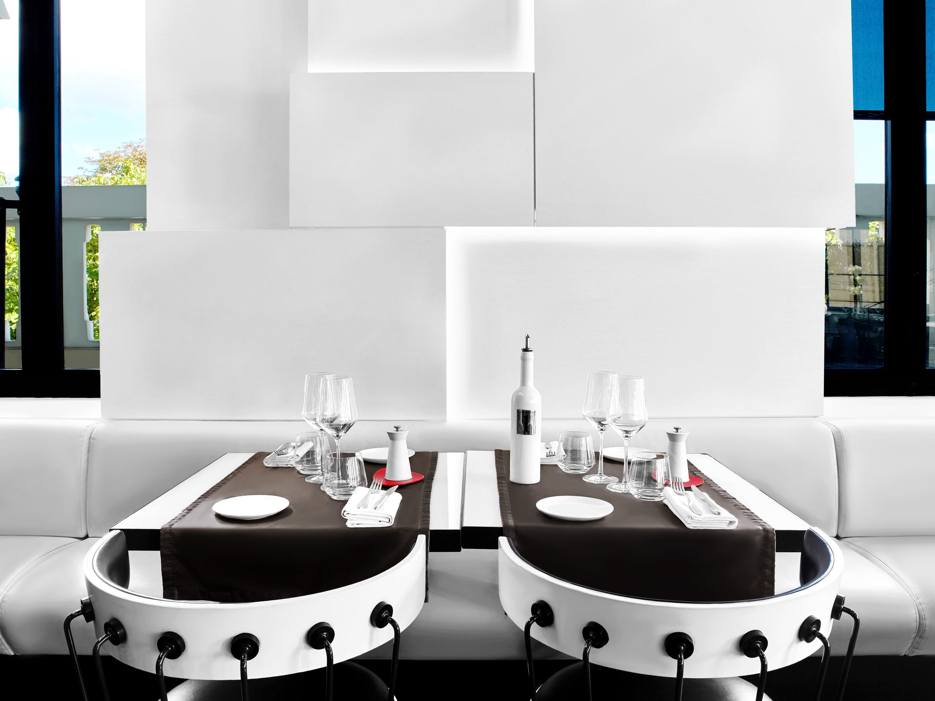 Nolita Paris — vue 23 — tables jumelles vues de face, chaises blanches cloutées au premier plan, sol miroir et parois blanches sculptées en gradins