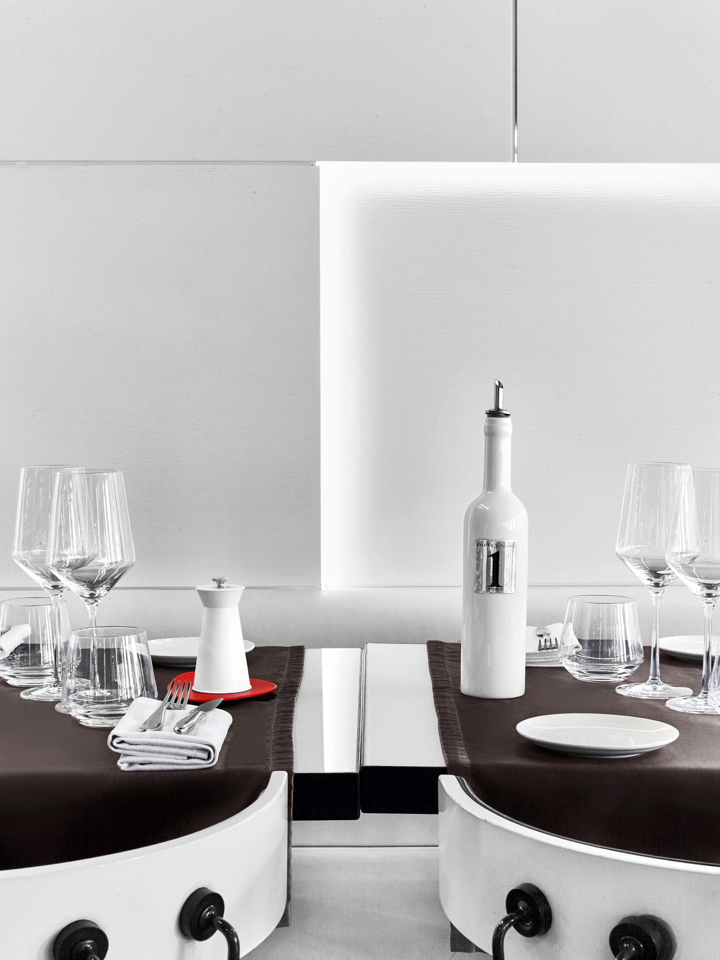 Nolita Paris — vue 25 — détail nature morte serré vertical, bouteille Assolo Galateo & Friends, dessous-de-plat rouge, verres en cristal et baie vitrée