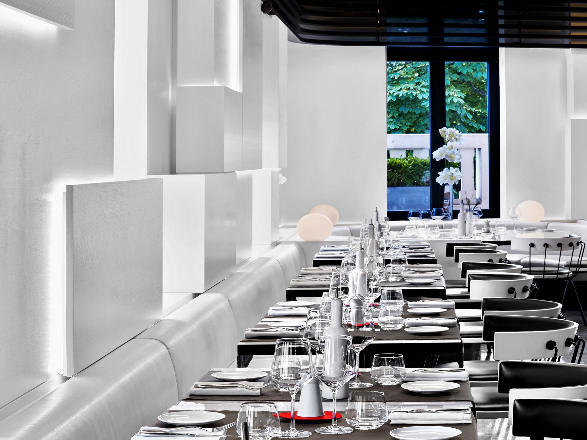 Nolita Paris — vue 28 — détail plongée sur table dressée, grappe de verres en cristal, dessous-de-plat rouge et bouteille Assolo sur nappe brune