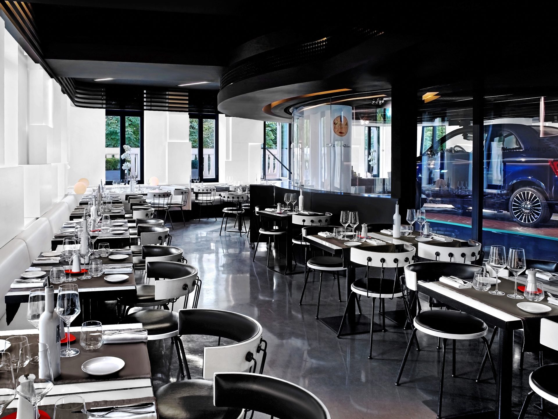 Nolita Paris — vue 29 — enfilade de tables en perspective, banquette latérale immaculée et mobilier circulaire noir et blanc