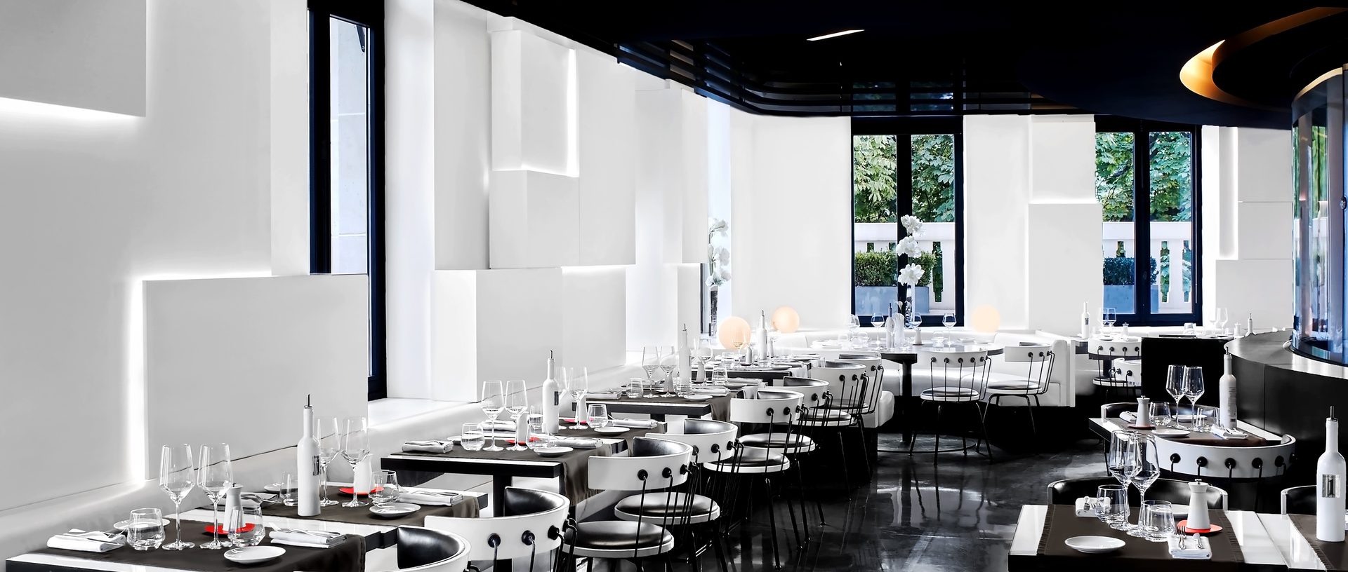 Nolita Paris — vue 32 — panorama très large de la salle entière, enfilade complète des tables et chaises, alcôve Fiat 500 à droite et courbes signature Wilmotte