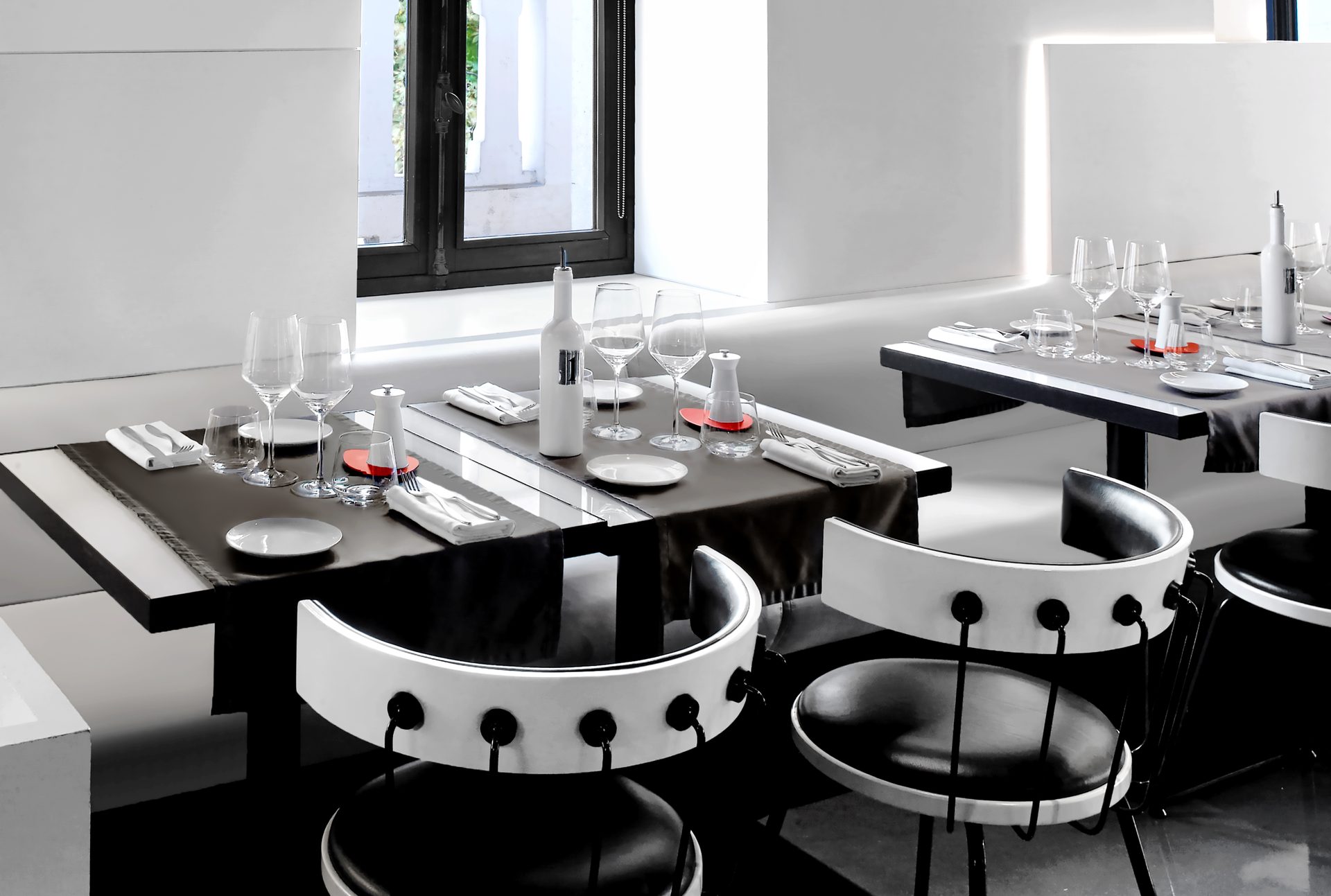 Nolita Paris — vue 36 — détail table dressée d'angle, verres en cristal, bouteille Assolo et signal rouge, ambiance noire et blanche en plongée