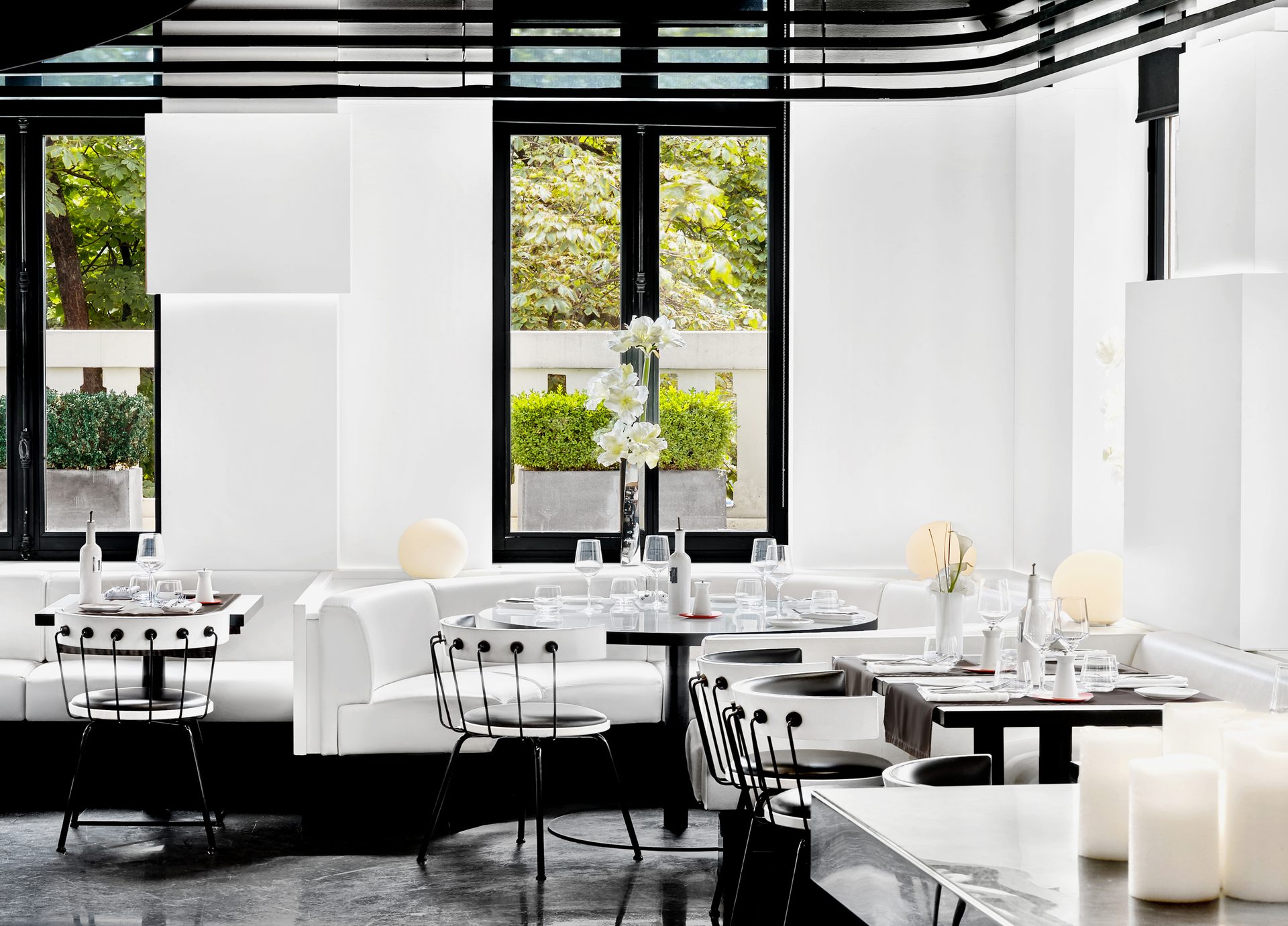 Nolita Paris — salle haute du restaurant italien, banquettes blanches et plafond rayé noir et blanc Wilmotte, baies vitrées sur arbres avenue Matignon Paris 8e