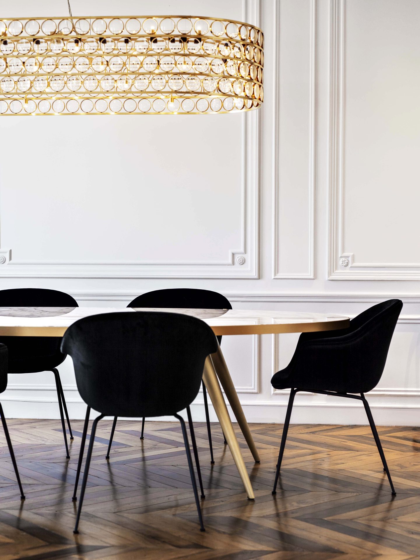Appartement au Trocadéro — vue 07 — table de salle à manger et chaises velours noir, suspension laiton à pastilles, parquet à chevrons