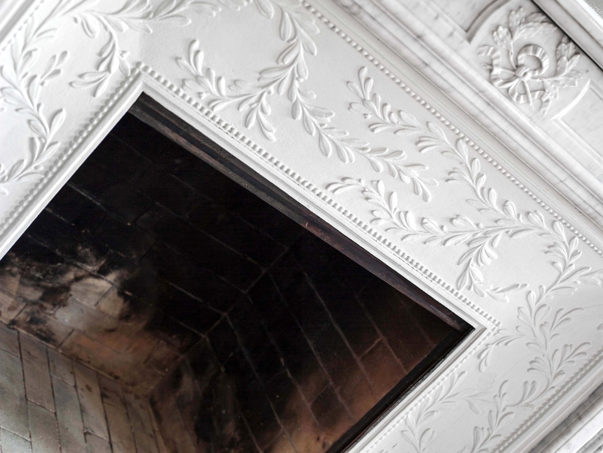 Appartement au Trocadéro — vue 13 — détail de cheminée en marbre blanc finement sculpté, motifs de feuillage et perles