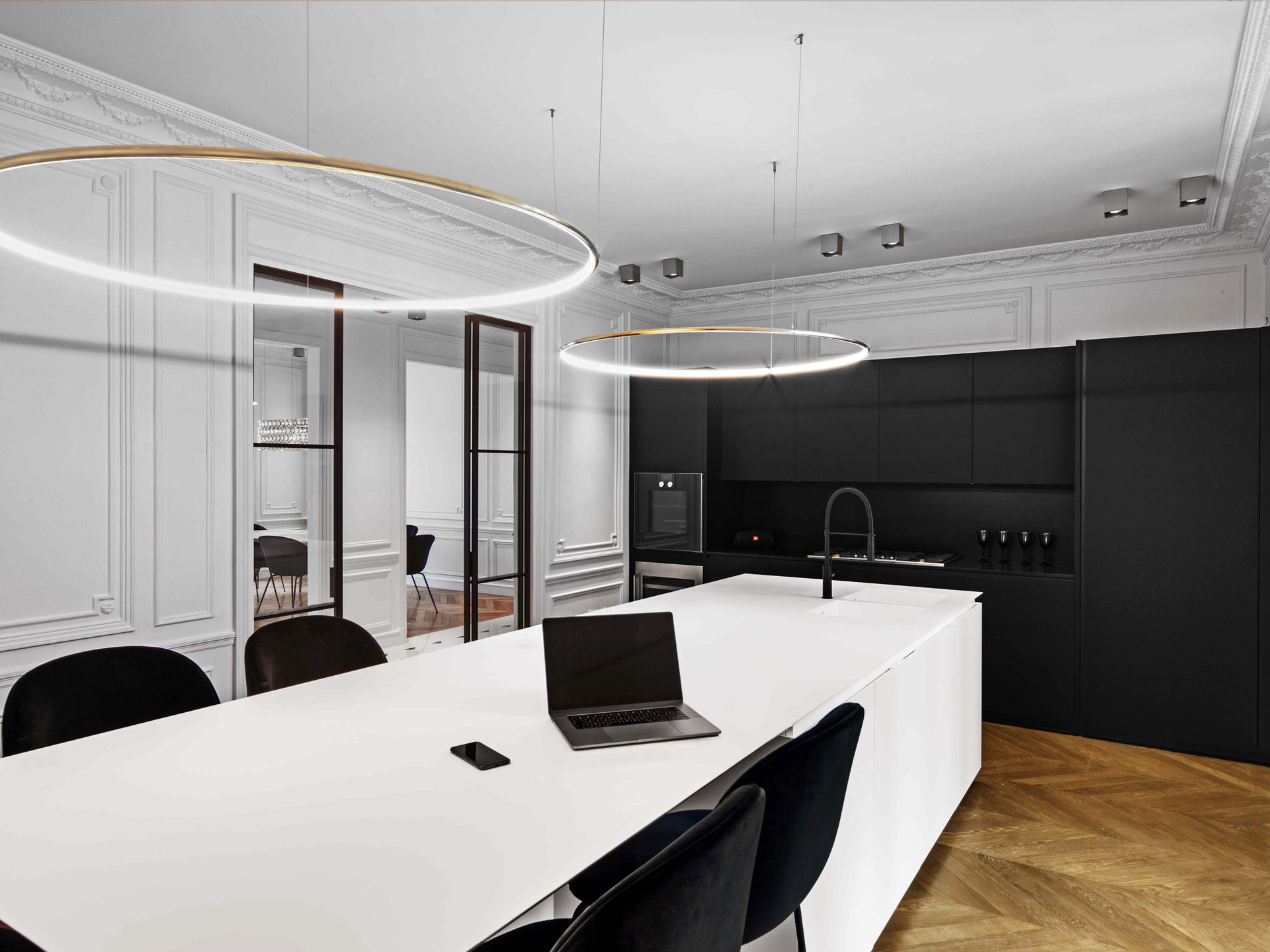 Appartement au Trocadéro — vue 19 — perspective cuisine et îlot vers la verrière, mobilier noir mat et anneaux lumineux
