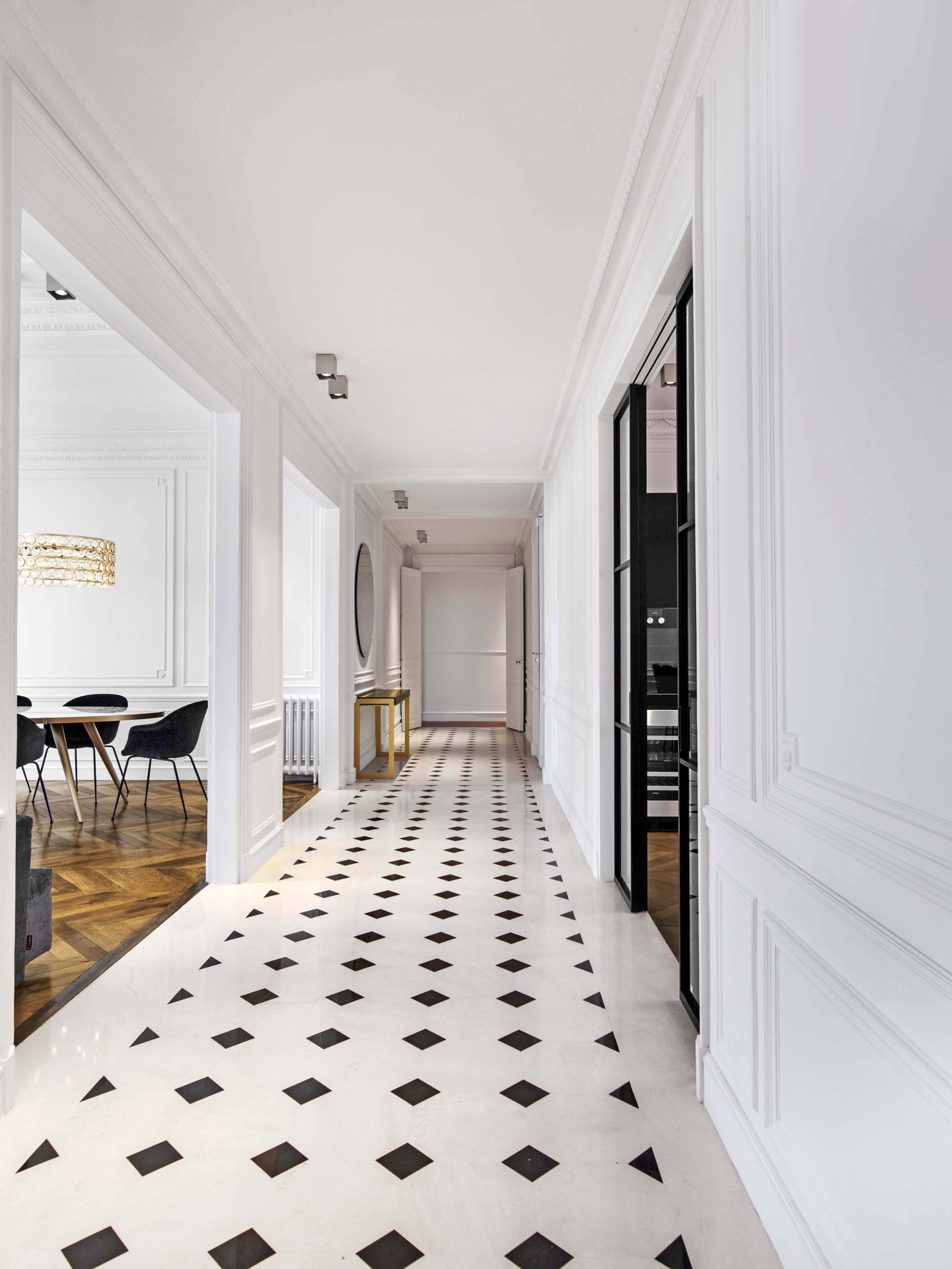 Appartement au Trocadéro — vue 37 — détail d'angle d'une console à plateau noir et piètement laiton, moulures et fauteuil sombre en arrière-plan