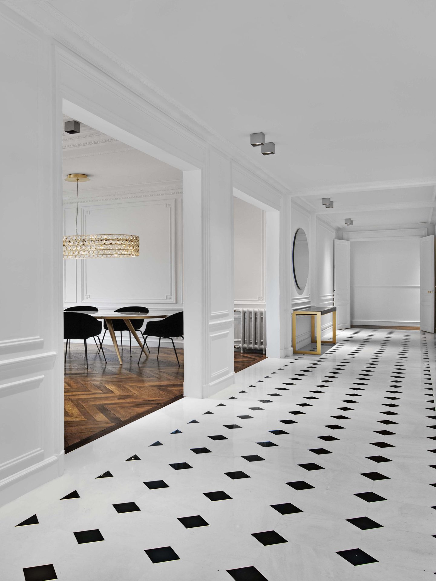 Appartement au Trocadéro — vue 39 — hall et galerie, sol damier marbre, console laiton et miroir rond, lustre à pastilles dans la salle à manger