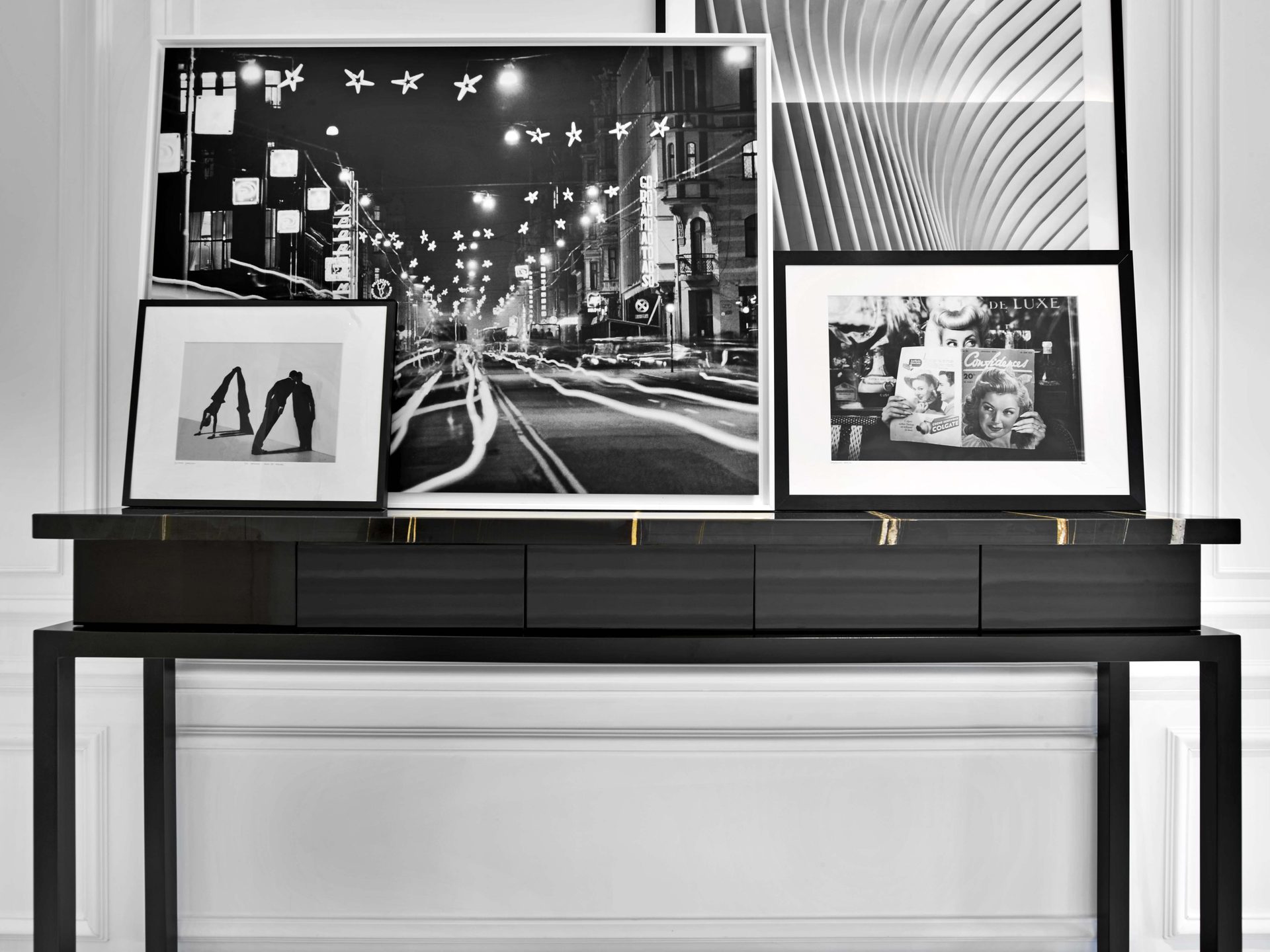 Pereire — vue 02 — détail de la console noire à plateau de marbre, photographies noir et blanc encadrées posées contre le mur à boiseries