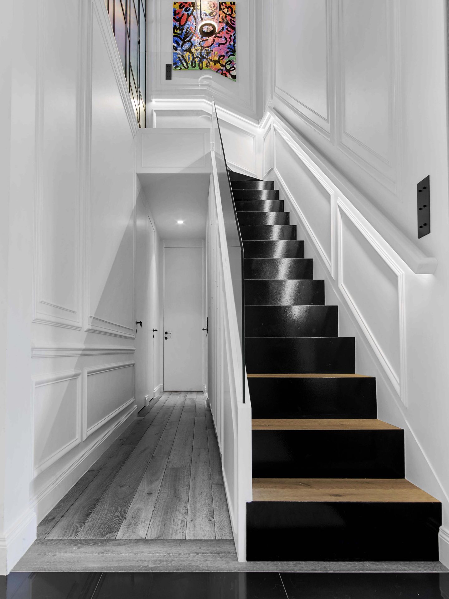 Pereire — vue 10 — escalier noir laqué et marches bois, couloir à boiseries, toile colorée en haut des marches