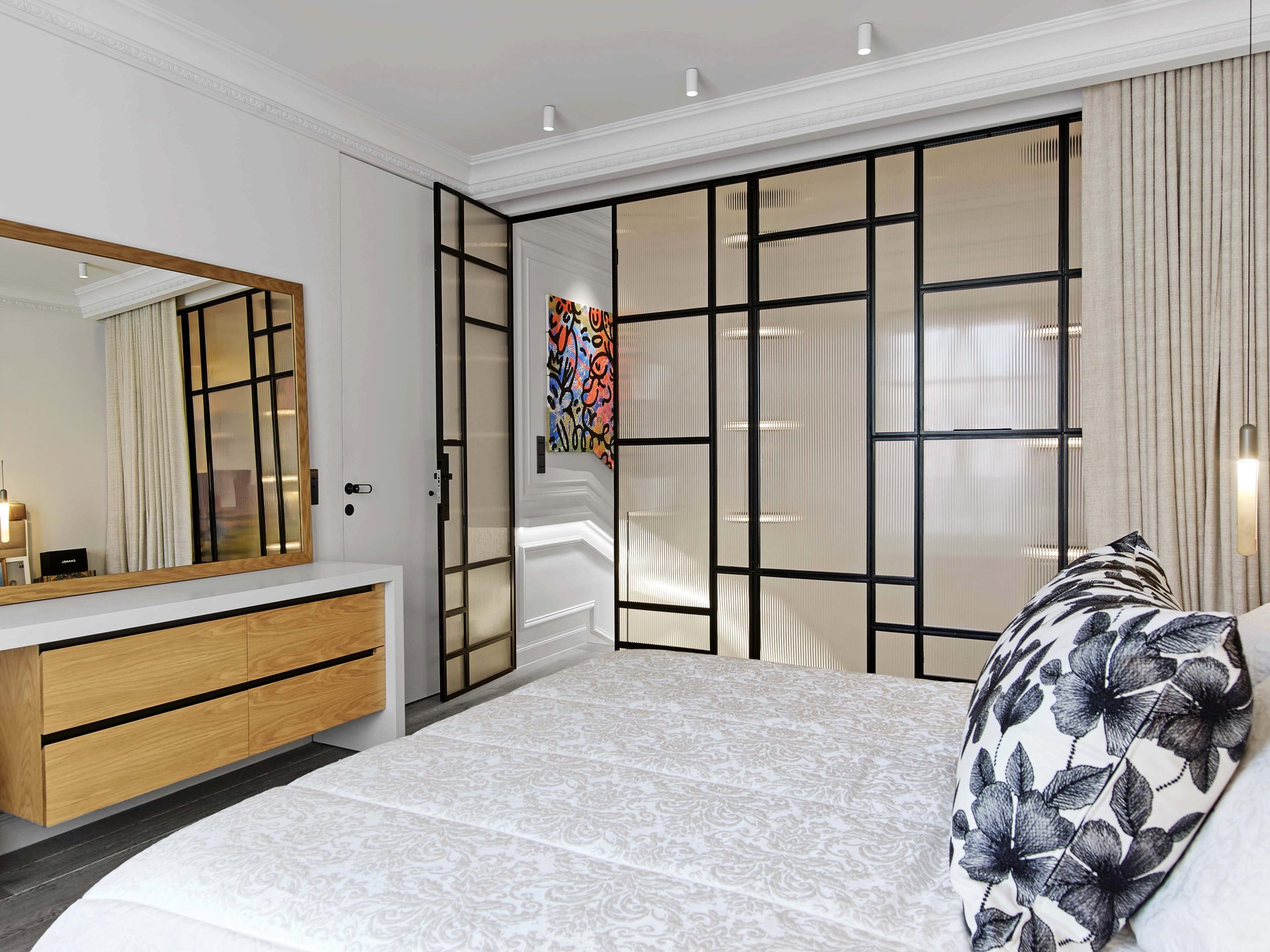 Pereire — vue 29 — chambre, grand miroir à cadre chêne au-dessus d'une console laquée et tiroirs bois, verrière d'atelier et toile street-art colorée