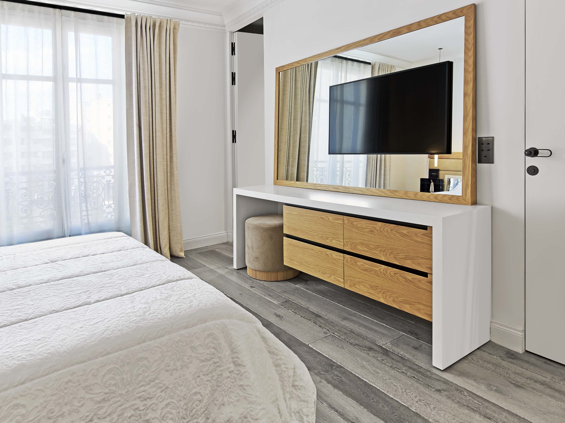 Pereire — vue 33 — chambre, miroir à cadre chêne reflétant le téléviseur, console laquée et tiroirs chêne, rideaux beige et fenêtre à ferronnerie