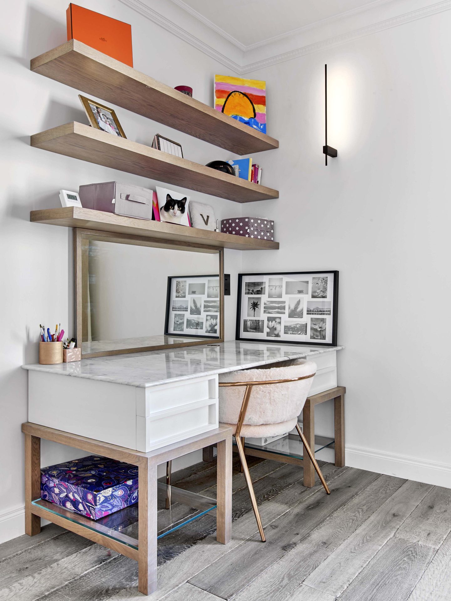 Pereire — vue 42 — chambre d'enfant, bureau-coiffeuse à plateau de marbre et miroir, étagères de chêne, séries de photographies noir et blanc encadrées, fauteuil en peau lainée