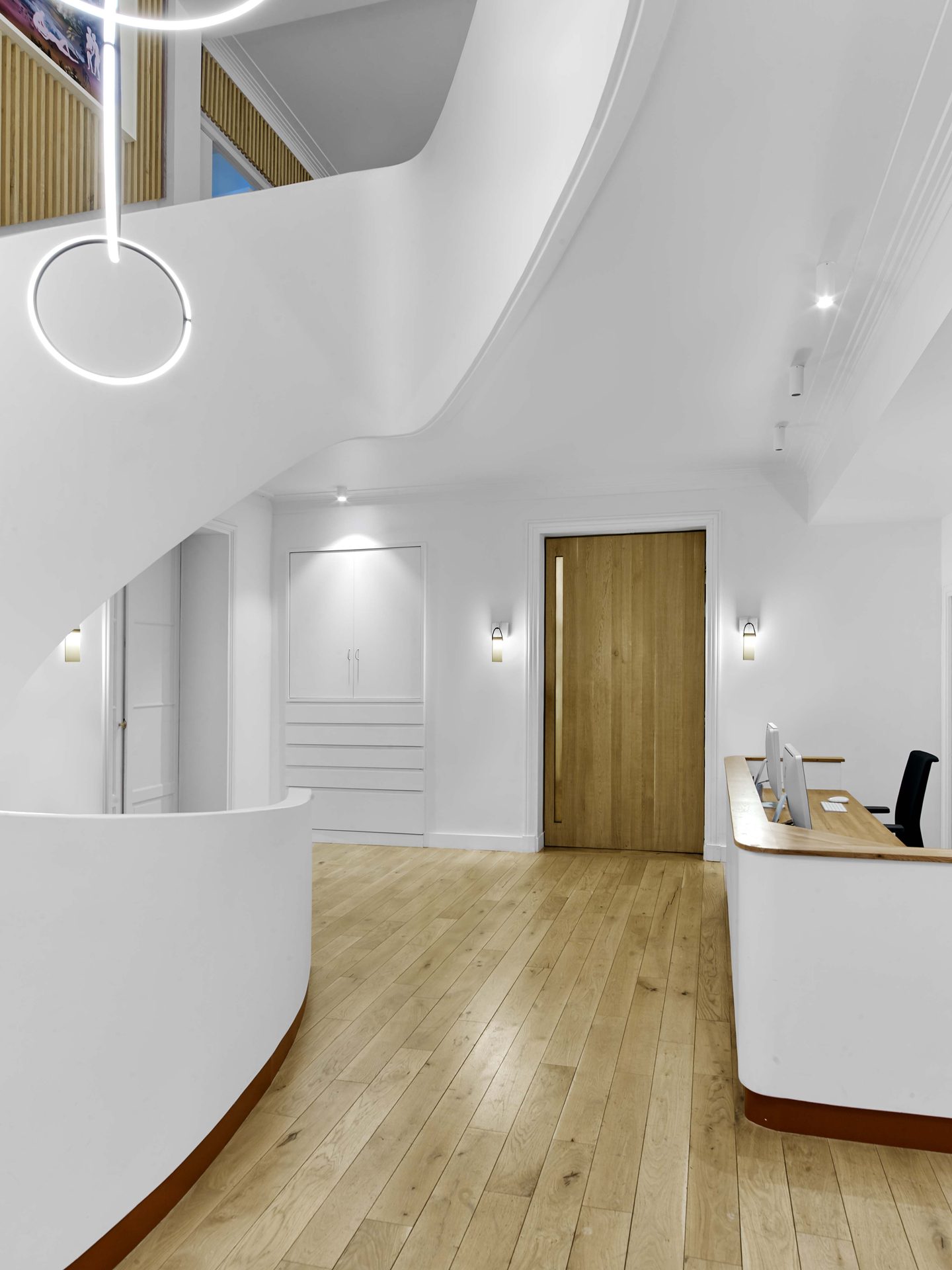 Beaux Arts — vue 01 — espace d'accueil, escalier blanc sculptural et comptoir, mur de tasseaux de chêne
