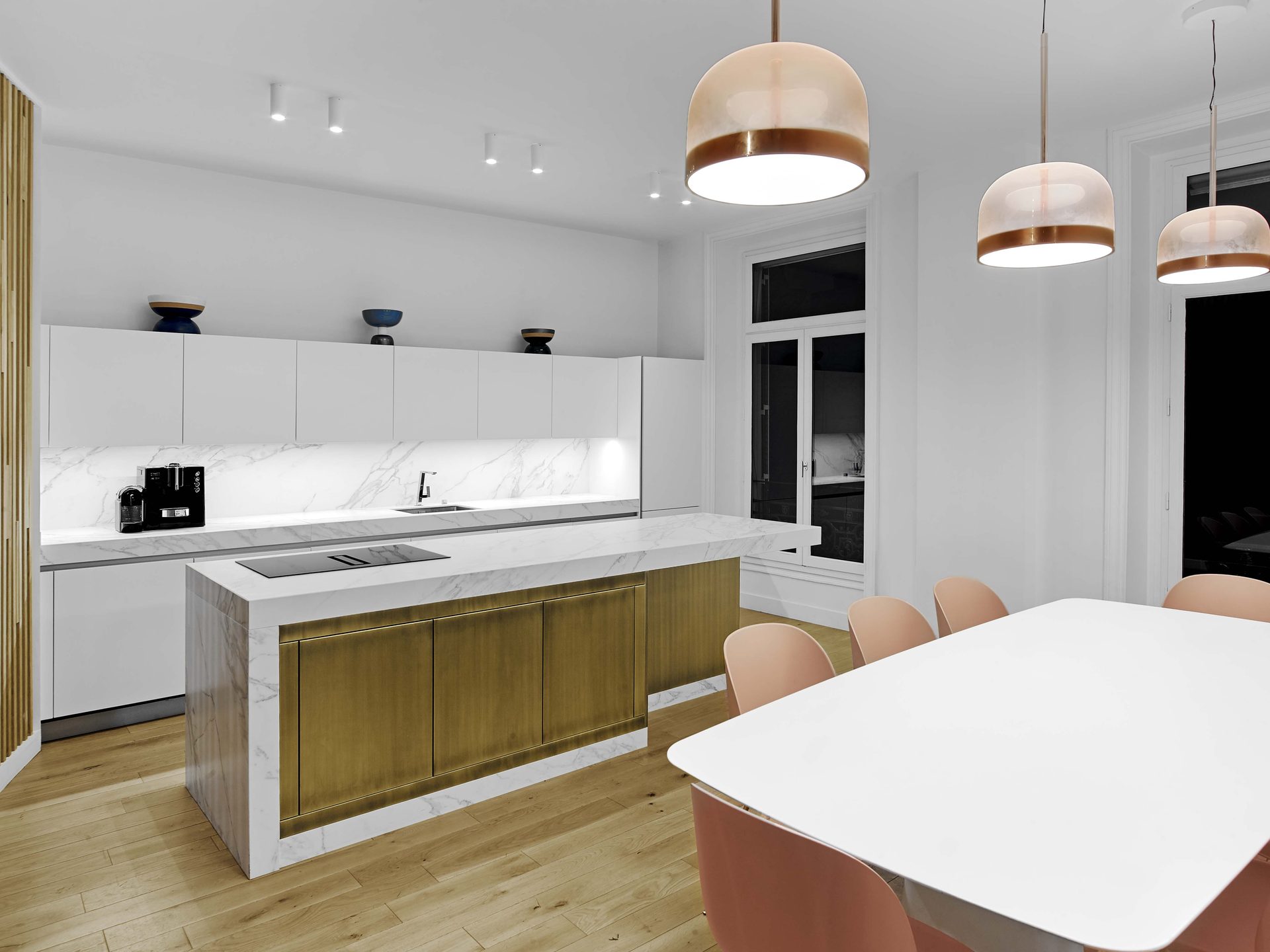 Beaux Arts — vue 49 — cuisine sous suspensions laiton, îlot de marbre et chaises roses