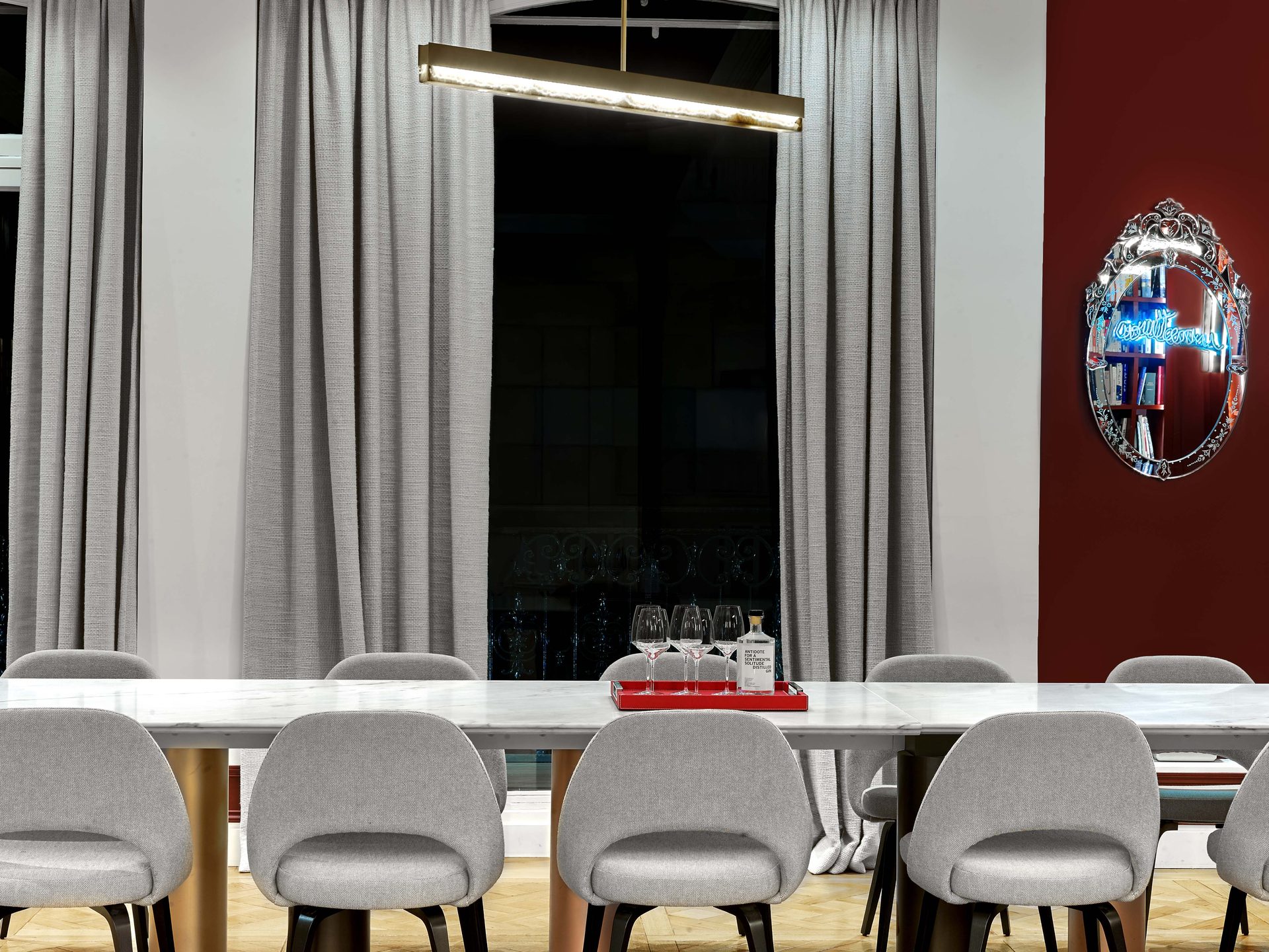 Beaux Arts — vue 57 — salle à manger aux murs rouges, chaises grises et miroir vénitien à néon