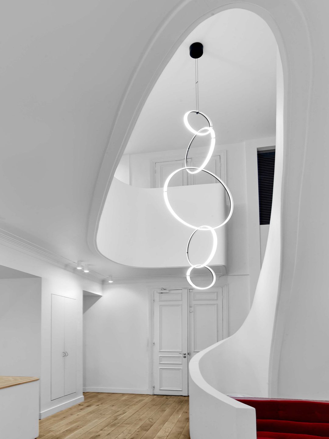 Accueil avec escalier sculptural blanc retouché — blancs homogènes, lumière équilibrée